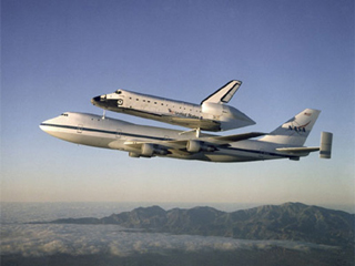 A photo of the Space Shuttle Atlantis, attached to the top of a Boeing 747 in flight for relocation. A photo of the Space Shuttle Atlantis, attached to the top of a Boeing 747 in flight for relocation.