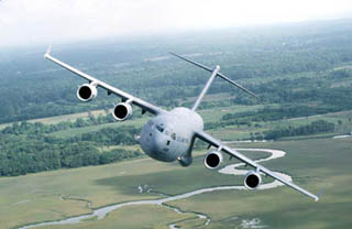 Photo of C-17 transport aircraft banking over a field. Photo of C-17 transport aircraft banking over a field.