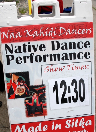 Sidewalk sandwich board advertises the next dance performance at 12:30 by the Naa Kahidi Dancers, located in Sitka, Alaska. Sidewalk sandwich board advertises the next dance performance at 12:30 by the Naa Kahidi Dancers, located in Sitka, Alaska.