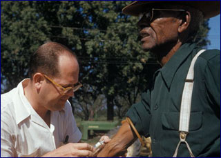 A white doctor gives a shot in the arm of an elderly black man. A white doctor gives a shot in the arm of an elderly black man.