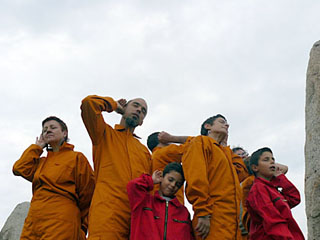 Photo of a small group of adults and children, wearing colored jumpsuits and in various poses of concentrated listening. Photo of a small group of adults and children, wearing colored jumpsuits and in various poses of concentrated listening.