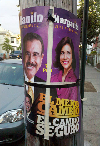 A colorful poster with a smiling man and woman is attached to a telephone pole. A colorful poster with a smiling man and woman is attached to a telephone pole.
