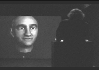 A black and white photo of a computer-rendered head projected on a screen. A black and white photo of a computer-rendered head projected on a screen.
