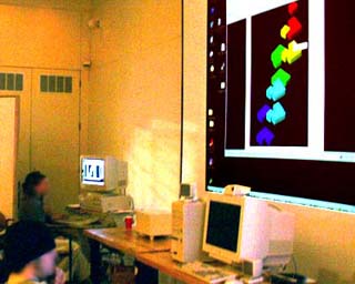 Photo of students seated at computers while watching a projected computer screen displaying their collaborative work with students at Miyagi University in Japan. Photo of students seated at computers while watching a projected computer screen displaying their collaborative work with students at Miyagi University in Japan.