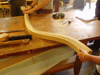 A wood-bending demonstration. Three students bending wooden strips with their hands. A wood-bending demonstration. Three students bending wooden strips with their hands.