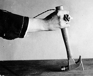 A black and white photo of a nail being pulled out of wood with a hammer. A black and white photo of a nail being pulled out of wood with a hammer.