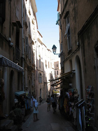 Photograph of a narrow, shaded street. Photograph of a narrow, shaded street.