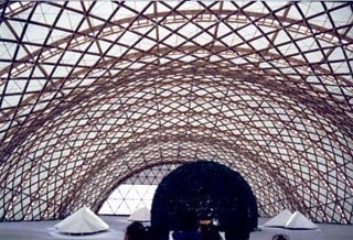 A photo of a large, arched metal superstructure above several geometric shapes. A photo of a large, arched metal superstructure above several geometric shapes.