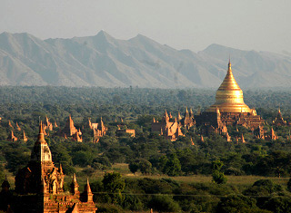Photo showing many temples and stupas on a plain, with a mountain range in the background. Photo showing many temples and stupas on a plain, with a mountain range in the background.