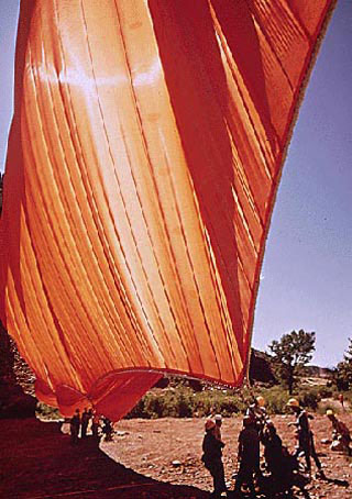 A tremendous orange cloth being hoisted into the air by teams of workers. A tremendous orange cloth being hoisted into the air by teams of workers.