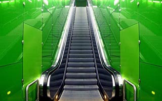 A photo of an escalator with green walls. A photo of an escalator with green walls.