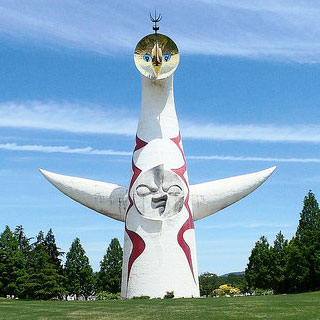 A photo of a cylindrical building with a face on it and outstretched arms. A photo of a cylindrical building with a face on it and outstretched arms.