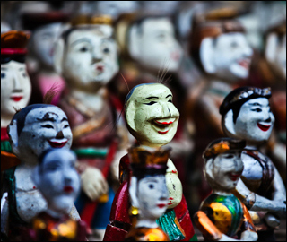 Photograph of small, brightly colored human-like figurines. Photograph of small, brightly colored human-like figurines.