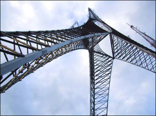 A tall, three-footed tower stretching into blue sky. A tall, three-footed tower stretching into blue sky.