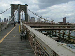 A photo looking down the middle of the pedestrian walkway on the Brooklyn Bridge. A photo looking down the middle of the pedestrian walkway on the Brooklyn Bridge.