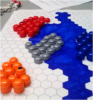 Colored pieces on a board of hexagons, many sided dice, and a sheet of rules. Colored pieces on a board of hexagons, many sided dice, and a sheet of rules.