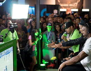 Gamers playing a video game at PAX 2015 while spectators watch. Gamers playing a video game at PAX 2015 while spectators watch.