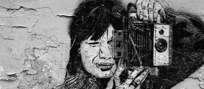 Photo of graffiti on a wall featuring a woman taking a picture. Photo of graffiti on a wall featuring a woman taking a picture.