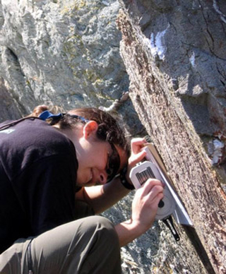 A student measuring the strike and dip of a rock face. A student measuring the strike and dip of a rock face.