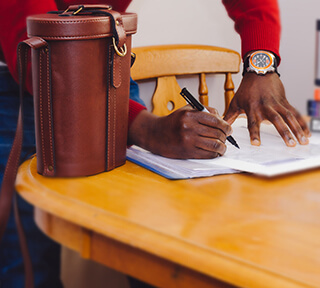 A man stands at a table and writes on a piece of paper. A man stands at a table and writes on a piece of paper.