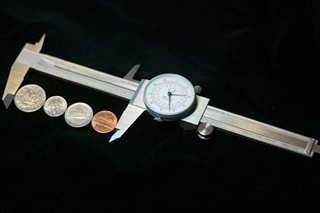 Photograph of four coins laid flat between the points of a caliper. Photograph of four coins laid flat between the points of a caliper.