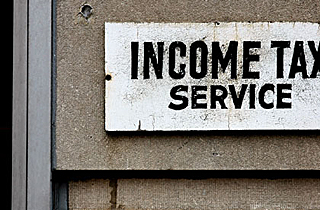Photograph of a white sign with black print advertising income tax preparation. Photograph of a white sign with black print advertising income tax preparation.