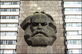 A huge bust of a bearded man sits in front of a multi-floored building. A huge bust of a bearded man sits in front of a multi-floored building.