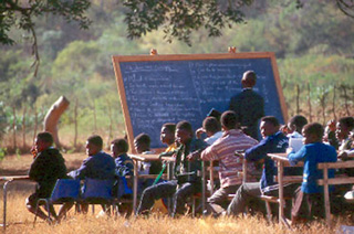 Students sit in a classroom in a grassy field. Students sit in a classroom in a grassy field.