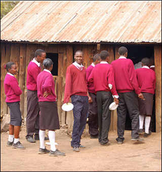 A photo of Kenyan teens wearing red school uniforms lined up outside. A photo of Kenyan teens wearing red school uniforms lined up outside.