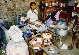 Photograph of a woman with stacks of food and medicinal supplies. Photograph of a woman with stacks of food and medicinal supplies.