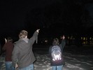 Photo of students pointing at an unseen object in the night sky.