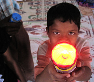 A young boy pointing a shining flashlight at the camera. A young boy pointing a shining flashlight at the camera.