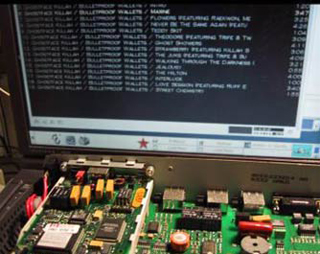 A photo of an exposed circuit board sitting in front of a monitor. A photo of an exposed circuit board sitting in front of a monitor.