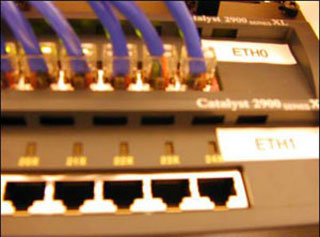Photo of the back of a network switch, with multiple ethernet cables plugged in. Photo of the back of a network switch, with multiple ethernet cables plugged in.
