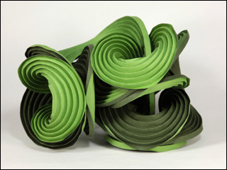 Green paper folded along multiple curved creases to form curved fins of a sculpture. Green paper folded along multiple curved creases to form curved fins of a sculpture.