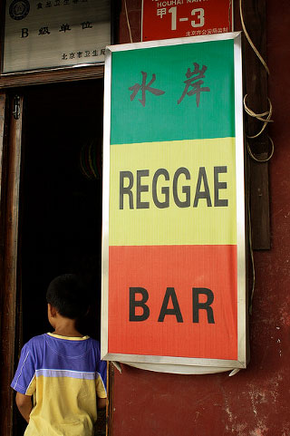A green, yellow, and red banner advertises a reggae bar in Mandarin and English. A green, yellow, and red banner advertises a reggae bar in Mandarin and English.