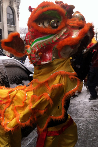 A photograph of a red, orange, and yellow Asian dragon costume on a snowy city street A photograph of a red, orange, and yellow Asian dragon costume on a snowy city street