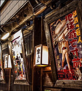 A photo of older movie posters outside of a wooden building. A photo of older movie posters outside of a wooden building.