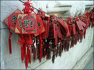A few bunches of red cards with red strings and tassels hanging on a cord on a wall. A few bunches of red cards with red strings and tassels hanging on a cord on a wall.
