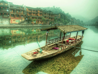 A Chinese wooden boat resting on still waters with reflection of ancient Chinese buildings along the riverbank. A Chinese wooden boat resting on still waters with reflection of ancient Chinese buildings along the riverbank.
