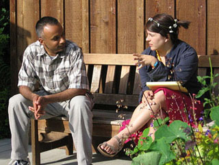Man and woman sitting on a bench, talking. Woman is gesturing. Man and woman sitting on a bench, talking. Woman is gesturing.