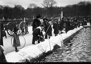 Photo of children in Luxembourg playing with toy sailboats on a pool in a public garden. Photo of children in Luxembourg playing with toy sailboats on a pool in a public garden.