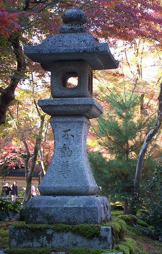 A photo of trees in the autumn and a small obelisk shaped stone with Japanese carved into it. A photo of trees in the autumn and a small obelisk shaped stone with Japanese carved into it.