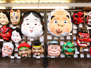 A number of Japanese masks hanging on a wall. A number of Japanese masks hanging on a wall.