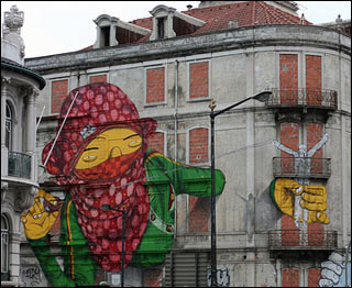 A large image of a woman in a green jacket and a red headscarf has been painted on the side of multi-story building. A large image of a woman in a green jacket and a red headscarf has been painted on the side of multi-story building.