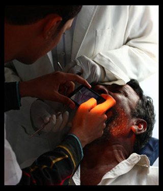 Photo of a health care worker taking a photo of the inside of a patient's mouth using a cell phone. Photo of a health care worker taking a photo of the inside of a patient's mouth using a cell phone.