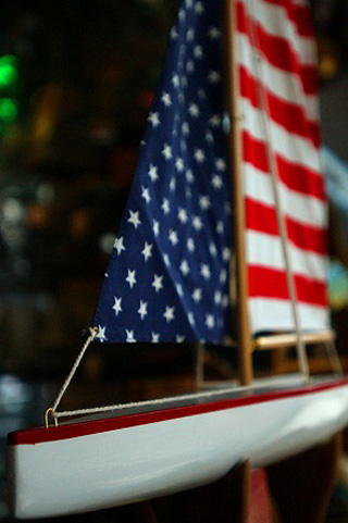 Photograph of a sailboat model with American flag motif sails. Photograph of a sailboat model with American flag motif sails.
