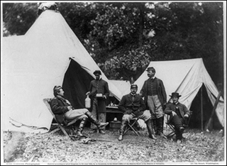 A photograph of civil war soldiers sitting in a camp. A photograph of civil war soldiers sitting in a camp.