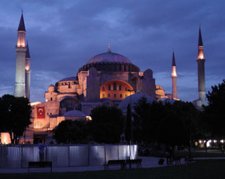 A night time view of an ornate structure with a rounded roof, framed by four pillars. A night time view of an ornate structure with a rounded roof, framed by four pillars.
