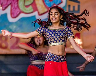 A young, brown-skinned girl with a smiling face dances, her long hair in motion. A young, brown-skinned girl with a smiling face dances, her long hair in motion.
